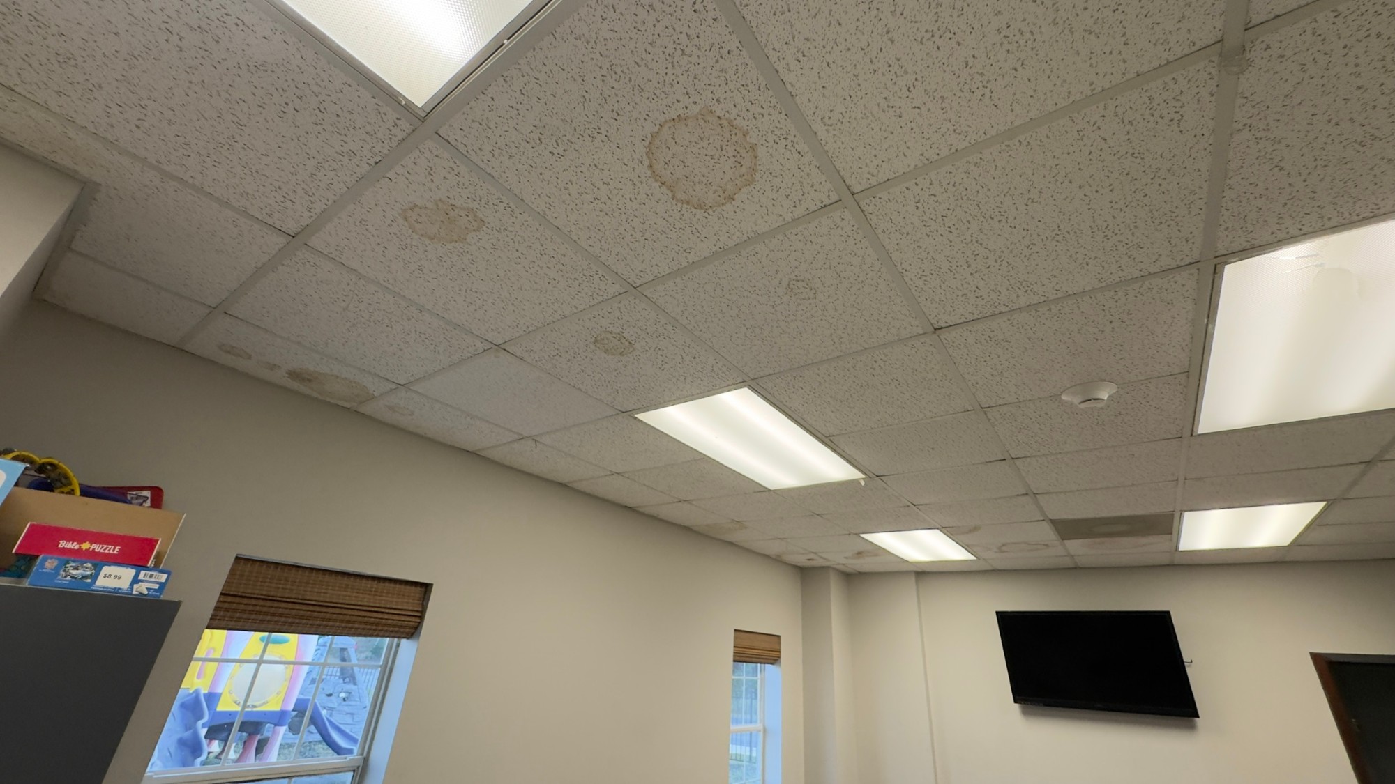 Water-stained ceiling tiles in a kids room before the renovation