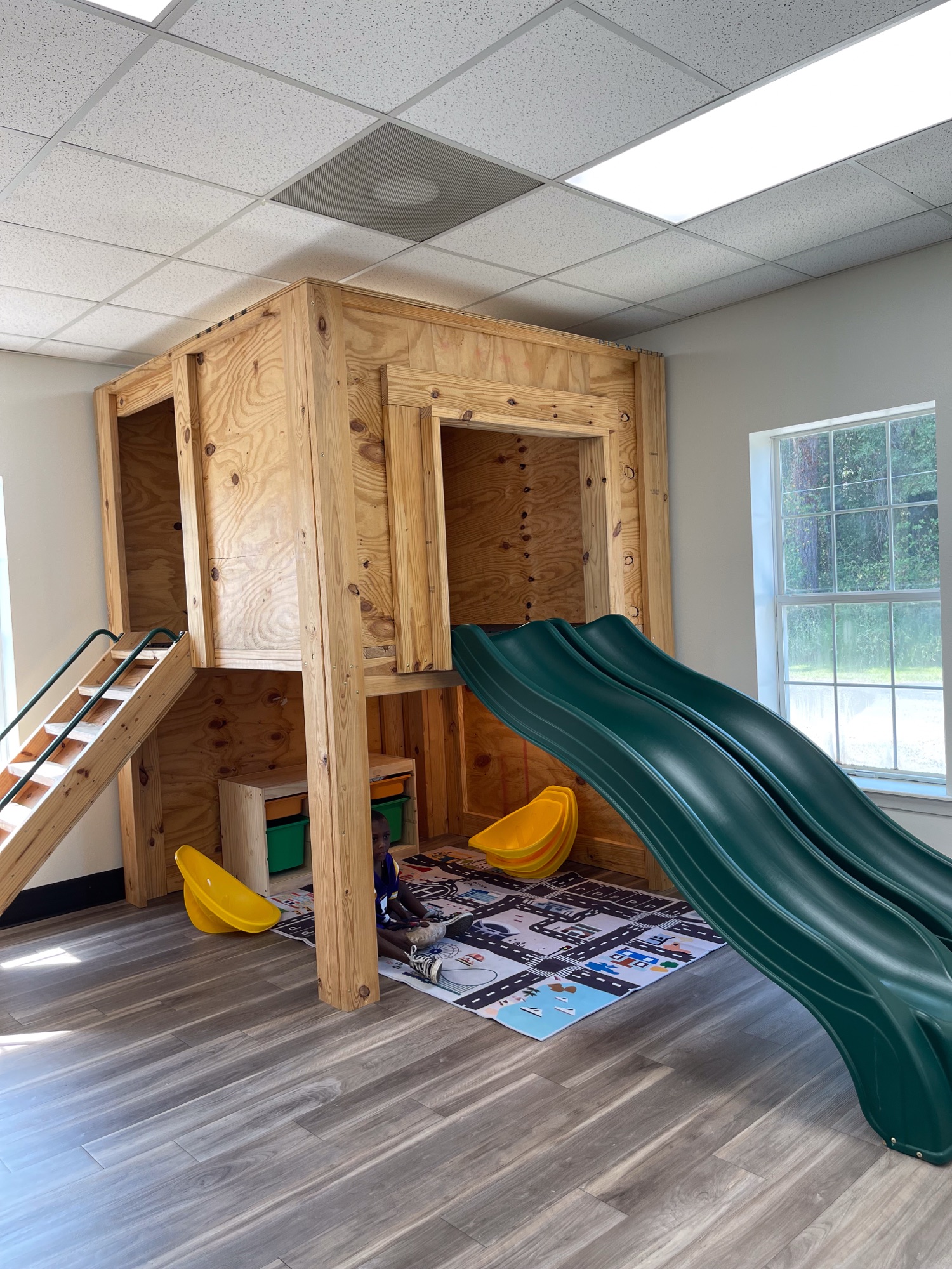 A wooden playhouse with a green slide in the Kids Wing